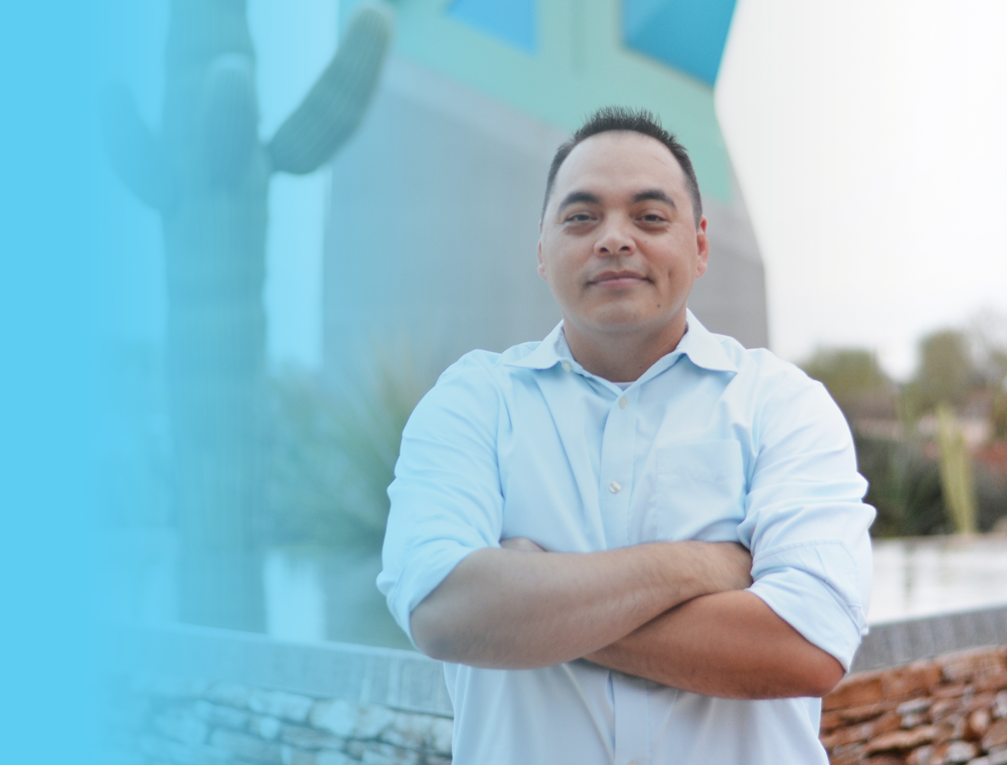 Brian Del Vecchio in front of a cactus with his arms crossed in a light blue button down shirt
